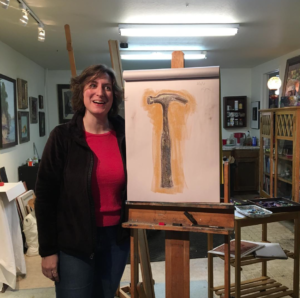 A picture of Anne in her art class, standing next to her large drawing of a hammer.